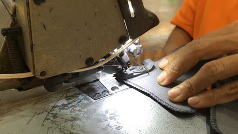 worker stitching on textile with overlock sewing machine