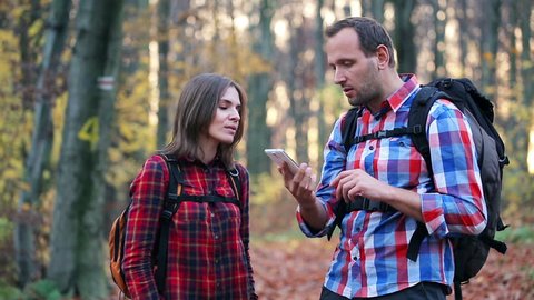 young couple with no network coverage in autumn forest

