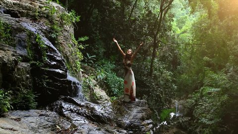 Young woman rises hands at waterfall in jungle Koh Samui. Thailand. HD. 1920x1080