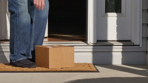 A man picks up a package from outside his front door.