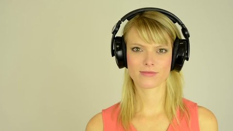 young attractive woman listens to music with headphones and smiles - studio