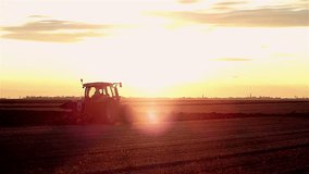 Tractor plowing field in sunset. Slow motion video,high speed camera.