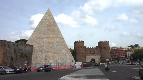 ROME - OCT. 2014: Cars pass through Porta San Paolo past Pyramid of Cestius, or Piramide; circa 18 BCE –12 BCE, later incorporated into Aurelian Walls, on left. Museo della Via Ostiense in castle.