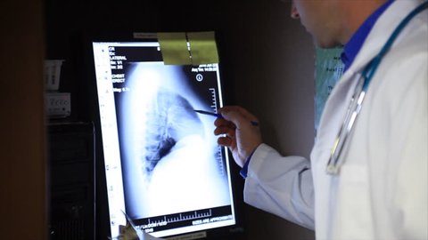 A doctor or technician analyzes the results of an x-ray on a computer screen.