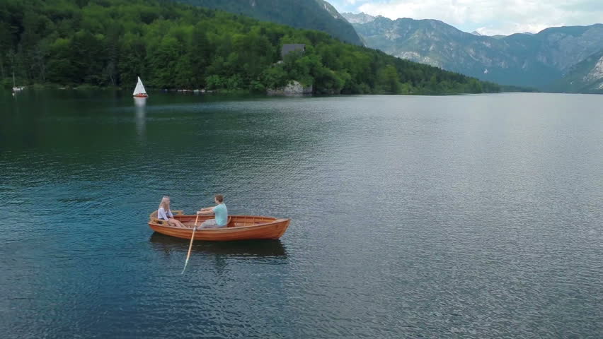 Heli shot of man rowing a boat. Aerial heli flying over shoot of a man rowing a boat to impress his date girl on a beautyfull lake Bohinj i Slovenia national park