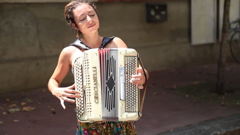 TOULOUSE, FRANCE - JULY 2014: Young woman playing the accordion in the streets of Toulouse. Playing street music, also known as busking, is popular in many cities in France.