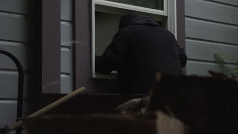 A burglar climbs through a house window - dolly movement - property released