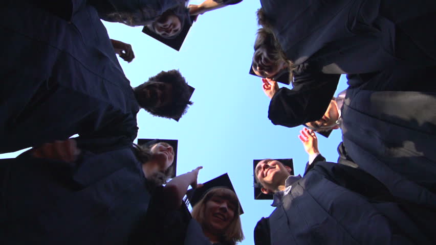 A slow-motion shot from below of a group of racially-diverse students throwing their graduation mortarboards in the air in celebration. Royalty-Free Stock Footage #7971607
