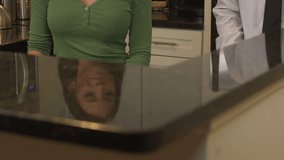 Young couple aged 25 to 30 years in kitchen, man embracing woman, both both smiling, close up, looking at camera at end of clip