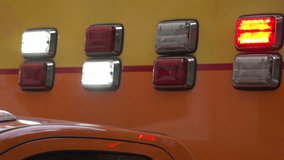 A close-up of lights flashing white and red on the side of a fire engine.