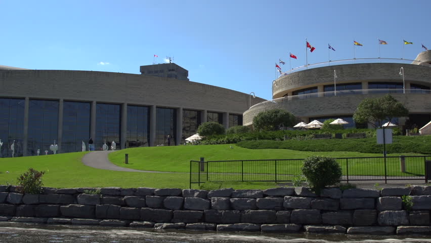 A pan right across the rear view of the Canadian Museum of History in Ottawa, Ontario, Canada. Tourists stand on the grass outside.