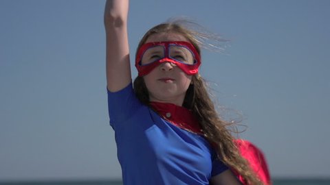 A close-up of a young girl, dressed as a superhero, striking a heroic pose.
