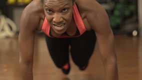 A close-up of her black female athlete, supported on her arms, goes through her fitness training motions, kicking each leg in turn, in slow motion. - property released