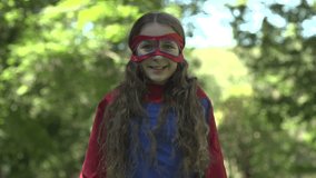 A superhero girl proudly expresses positivity with hands on her hips in triumph - slow motion