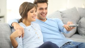 Young couple sitting in sofa and watching tv
