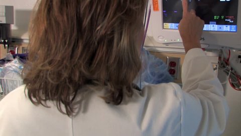 A nurse or doctor checks an EKG monitor.