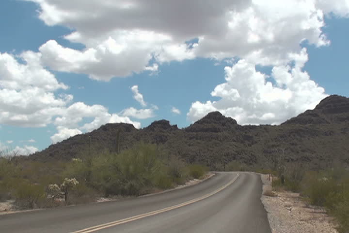 Time lapse, clouds roll over open road. NTSC