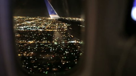 Airplane Window Seat - View of Los Angeles at Night and Wing of Plane on Flight, Traveling in Air over City Lights