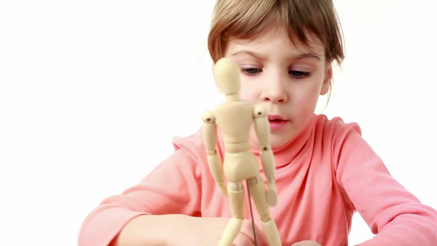 Little girl in red T-shirt raises arms and legs of human wooden figure and moves it up and down 