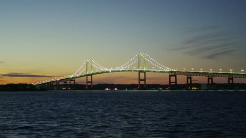 Newport Bridge in a wide shot with the bay in the foreground at night.
