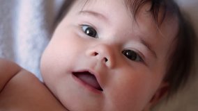 Little 5-month  baby girl is smiling. She is lying on the sofa. FullHD video