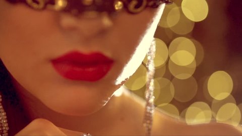 Beautiful sexy woman wearing venetian masquerade mask at party, over holiday glowing background. HD 1920x1080, slow motion 240 fps, high speed camera shot