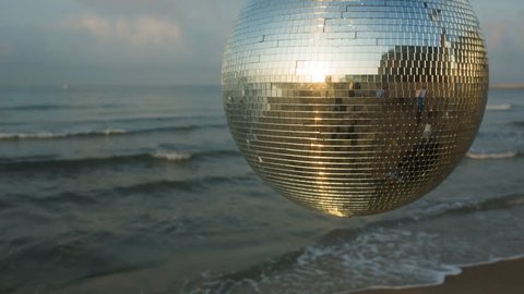 large spinning discoball on the beach with the sea in the background. very balearic clip useful for clubs, music and fashion events

