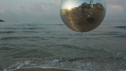 large spinning discoball on the beach with the sea in the background. very balearic clip useful for clubs, music and fashion events
