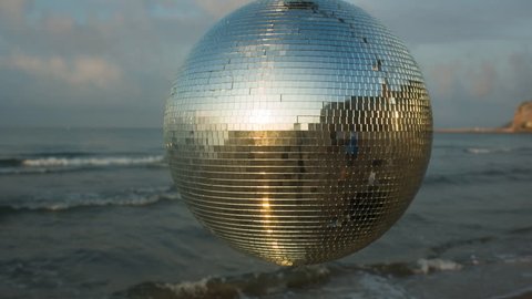 large spinning discoball on the beach with the sea in the background. very balearic clip useful for clubs, music and fashion events

