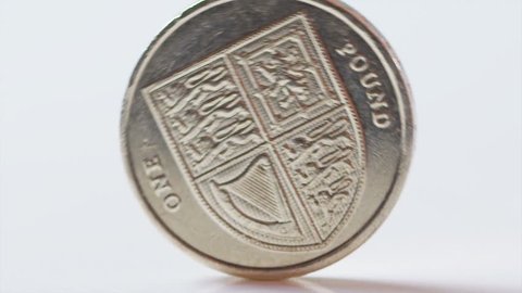 UK One pound coin rolling across the screen in slow motion, shot on RED EPIC