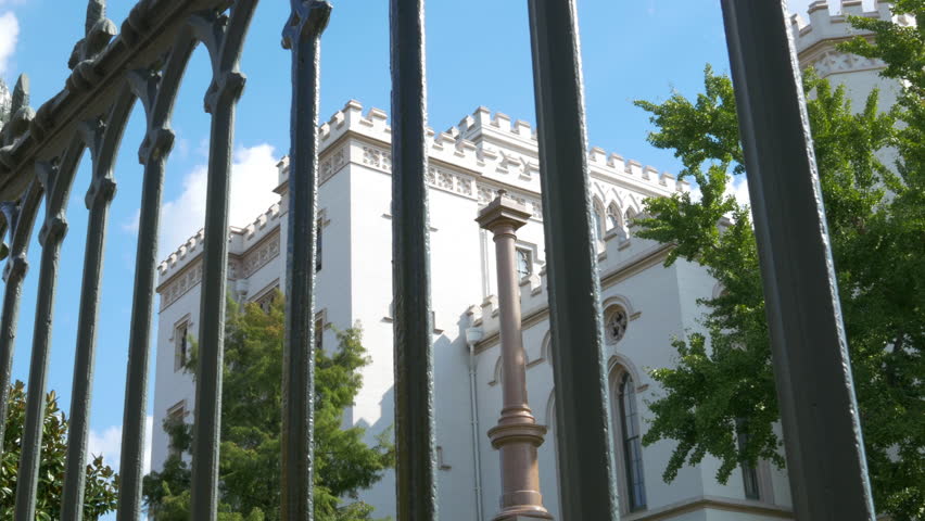 View through an ornate wrought iron fence to the historic old Louisiana state capital building in Baton Rouge built to resemble a Neo-Gothic medieval castle.