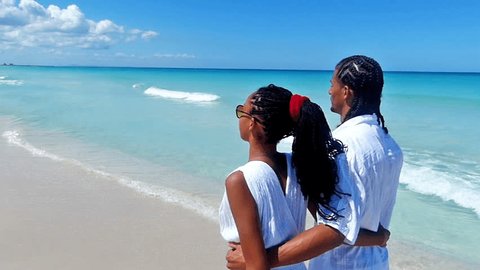 Rear view of young, hugging african american couple walking along a tropical beach.Slow motion, high speed camera