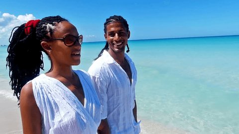 Happy, young african american couple walking along a tropical beach, pointing at something.Slow motion, high speed camera