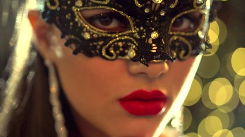 Sexy woman wearing venetian masquerade carnival mask at party, over holiday glowing background. Holiday make up and accessories. HD 1080p, slow motion 240 fps, high speed camera shot