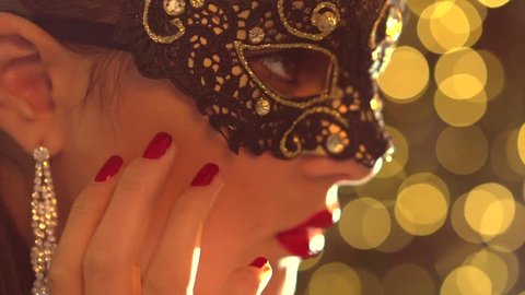 Sexy woman wearing venetian masquerade carnival mask at party, over holiday glowing background. Holiday make up and accessories. HD 1920x1080p, slow motion 240 fps, high speed camera shot