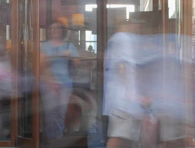People spinning in and out revolving door time lapse