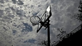 Low angle clip of outdoor basketball hoop in time lapse