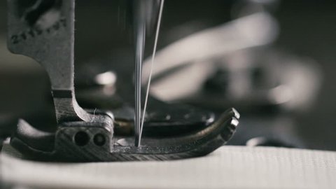 Super slow motion of vintage sewing machine stitching on white fabric (macro close up)