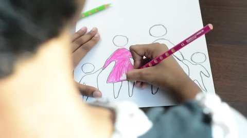 Close up of child drawing a family picture on paper - bird's eye view.