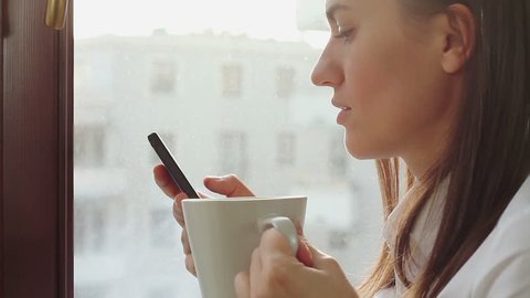 Young businesswoman drinking coffee and sending messages with her mobile phone