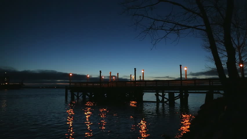 Fishing Pier Twilight, Ship Passing, Fraser River. A fishing pier on the bank of the Fraser River near Steveston at twilight as a barge travels downriver. Richmond, British Columbia, Canada.
