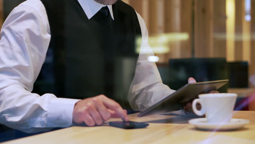 Man sitting in the restaurant and working on modern technolody, steadycam shot
