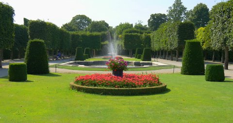 Beautiful garden landscape with flowers, green grass, fountain in the Schonbrunn royal imperial palace park in Vienna city (Wien), Austria, Europe. Summer travel to famous attraction place background