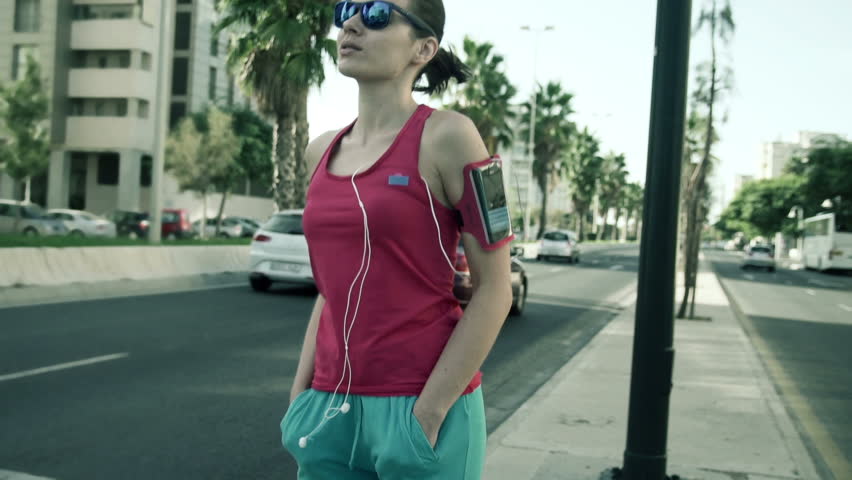 Young, attractive female jogger waiting on the pedestrian crossing
