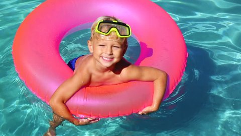Happy Young Boy Floating in Swimming Pool on Raft