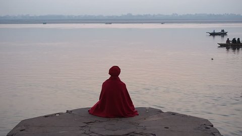 Varanasi, India - February 18: Sadhu (Indian holy man) sitting in meditation by the sacred Ganges river in Varanasi, Uttar Pradesh, India.