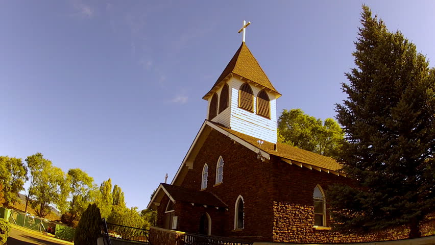 FLAGSTAFF, AZ: October 9, 2014- Low and wide angle shot of an old stone chapel, steeple and cross circa 2014 in Flagstaff. Zoom on focal point of church roof spire with ornamental religious symbol.