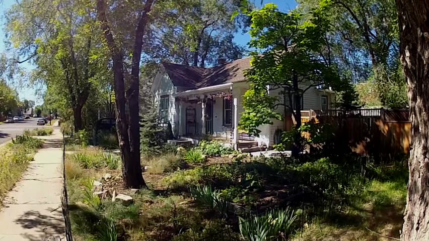 FLAGSTAFF, AZ: October 9, 2014- Old fashioned wooden frame house with porch in small town neighborhood circa 2014 in Flagstaff. A tiny home is surrounded by trees and shrubs on a suburban street.