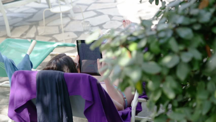 Woman Sunbathing and Using a Tablet