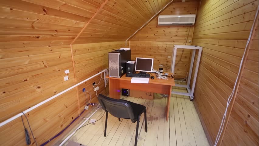 A small room in the attic decorated in wood with a work desk